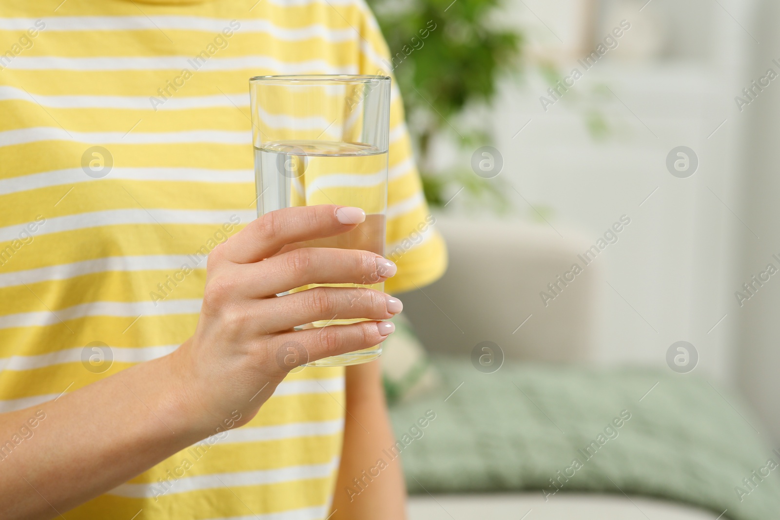 Photo of Healthy habit. Closeup of woman holding glass with fresh water indoors, space for text