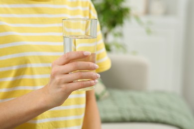 Healthy habit. Closeup of woman holding glass with fresh water indoors, space for text