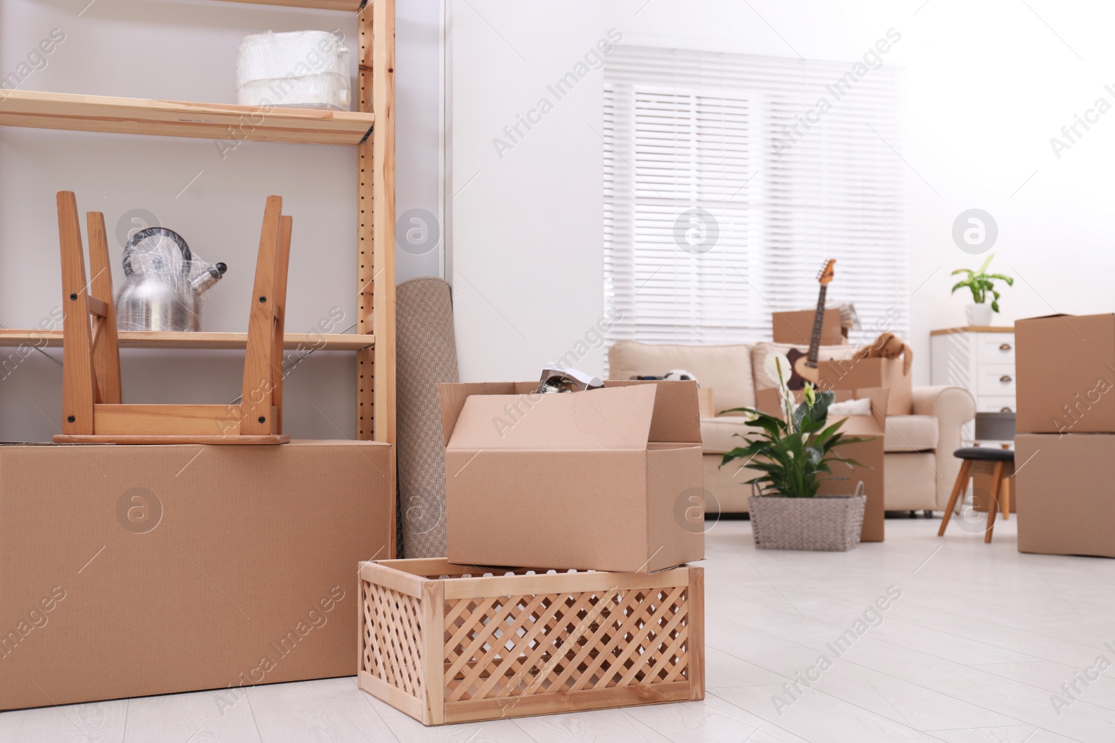 Photo of Cardboard boxes and household stuff in living room. Moving day