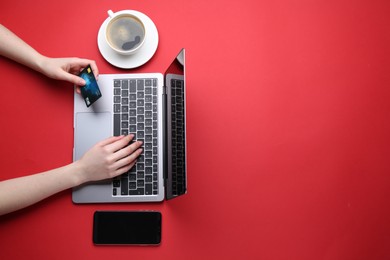 Online payment. Woman with laptop, smartphone and credit card on red background, top view. Space for text