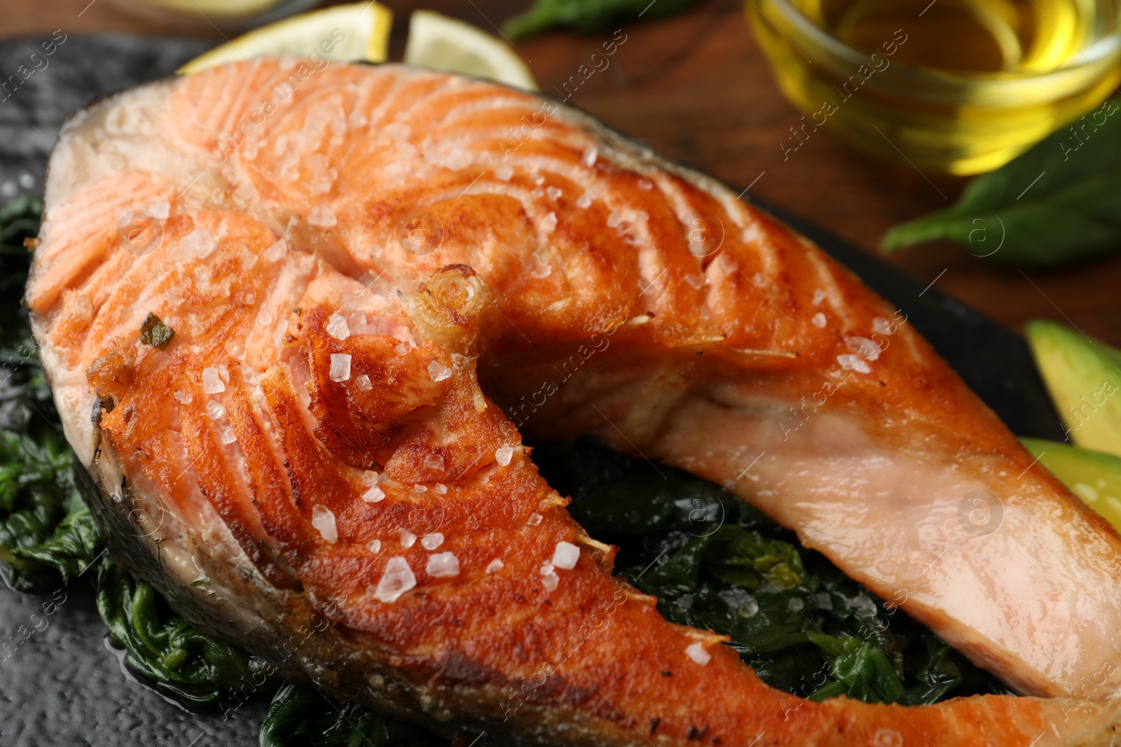 Photo of Tasty salmon with spinach served on table, closeup