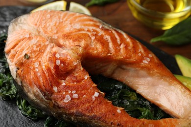 Photo of Tasty salmon with spinach served on table, closeup