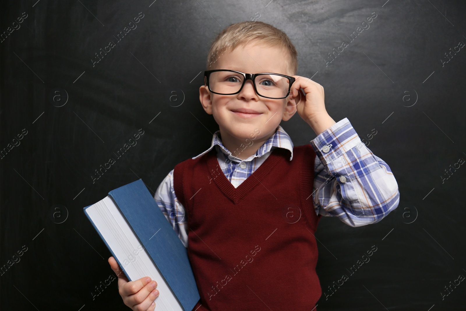 Photo of Cute little child wearing glasses near chalkboard. First time at school