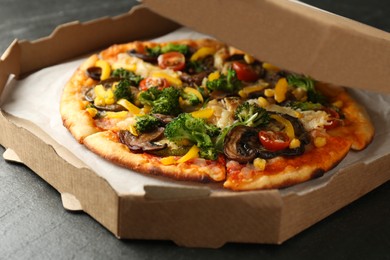 Photo of Delicious vegetarian pizza with mushrooms, cheese and vegetables in box on black table, closeup