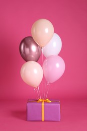 Photo of One gift box and balloons near bright pink background