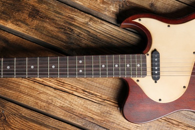 Photo of Modern electric guitar on wooden background, top view. Musical instrument