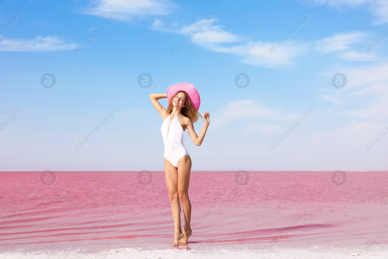 Photo of Beautiful woman in swimsuit posing near pink lake on sunny day