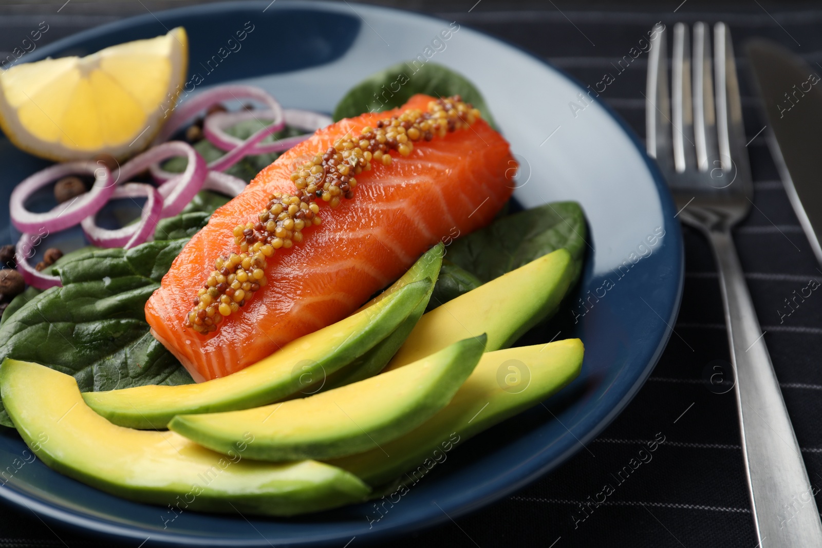 Photo of Delicious salmon with spinach and avocado served on fabric, closeup