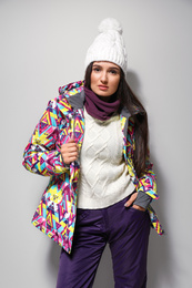 Woman wearing stylish winter sport clothes on light grey background