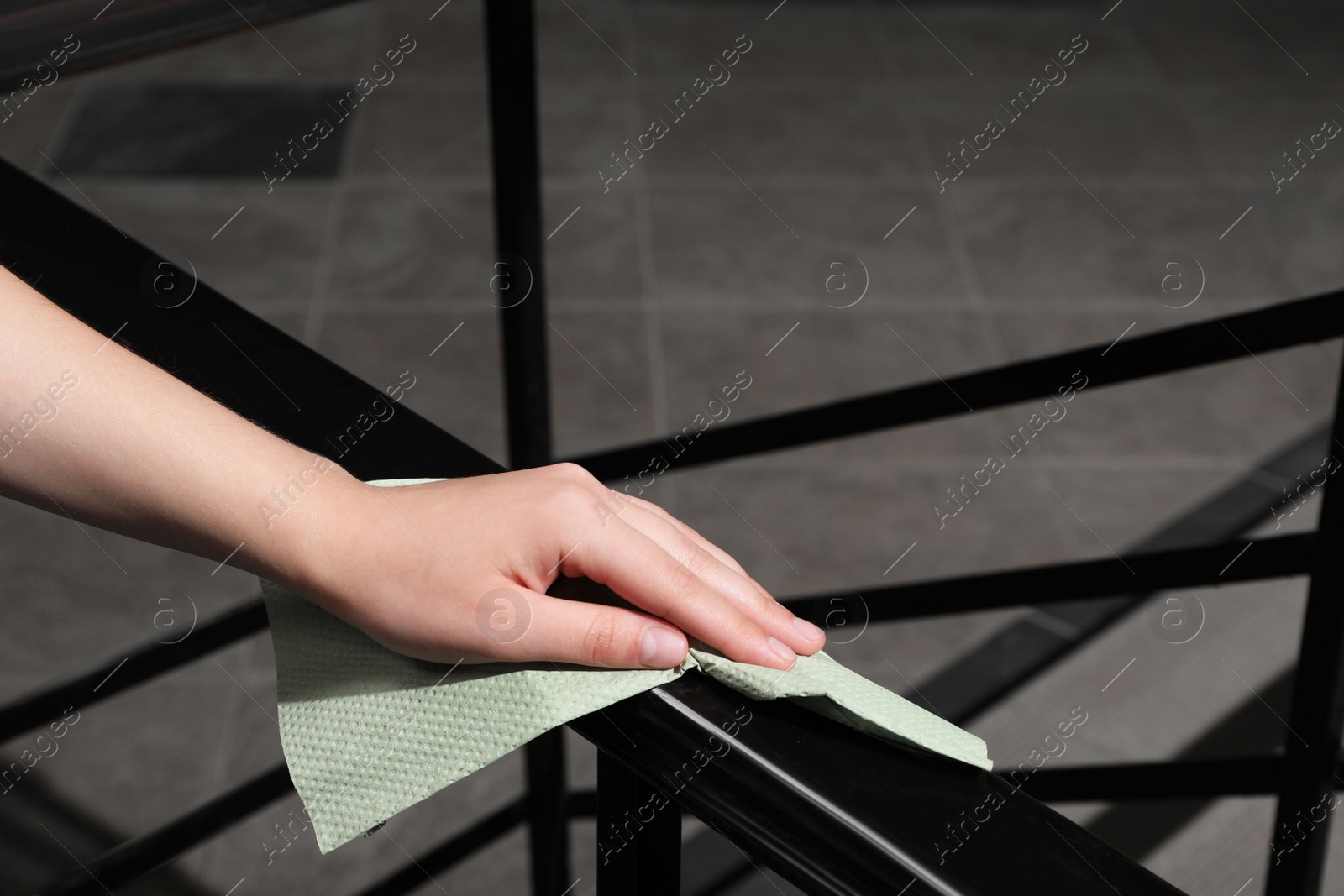 Photo of Woman cleaning railing with paper towel indoors, closeup