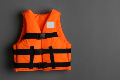 Photo of Orange life jacket on grey background. Space for text