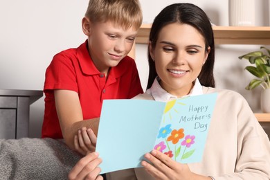 Photo of Happy woman receiving greeting card from her son at home