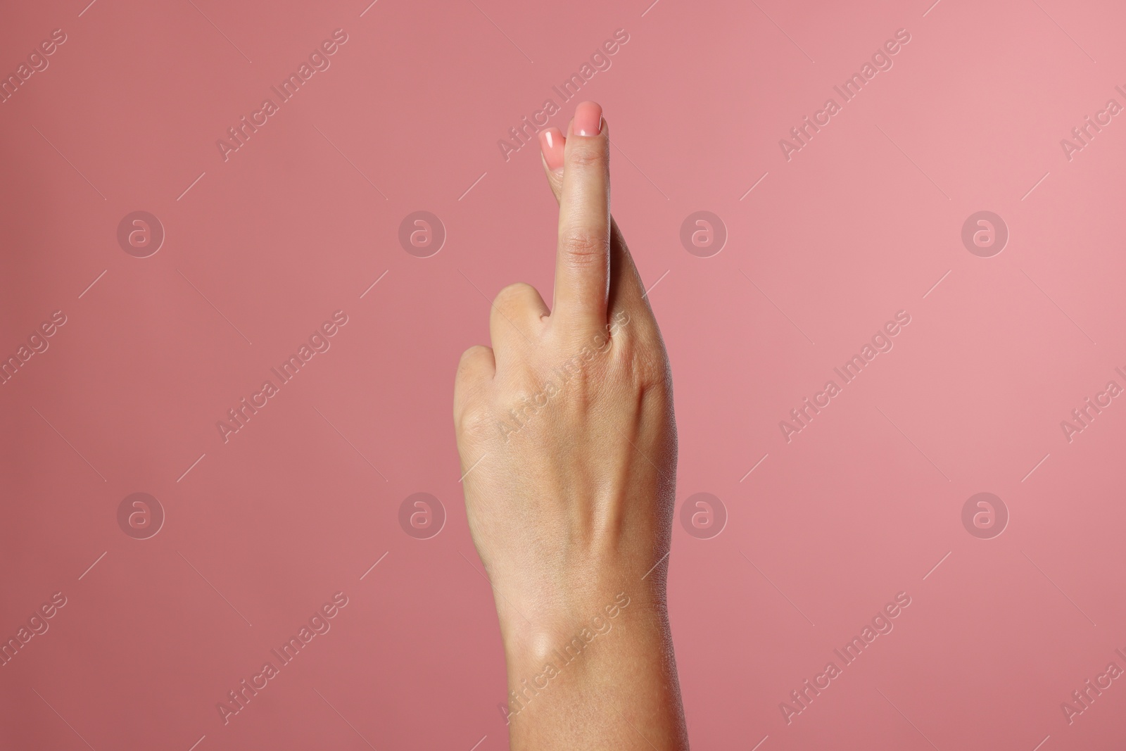 Photo of Woman crossing her fingers on pink background, closeup