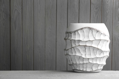 Photo of Stylish white ceramic vase on grey wooden table. Space for text