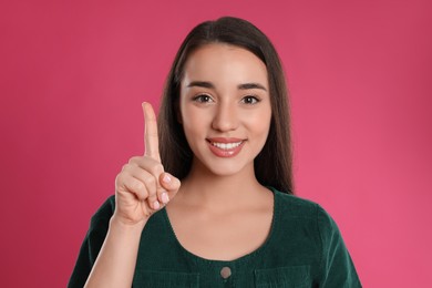 Photo of Woman showing number one with her hand on pink background