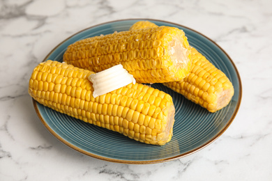 Delicious boiled corn with butter on white marble table