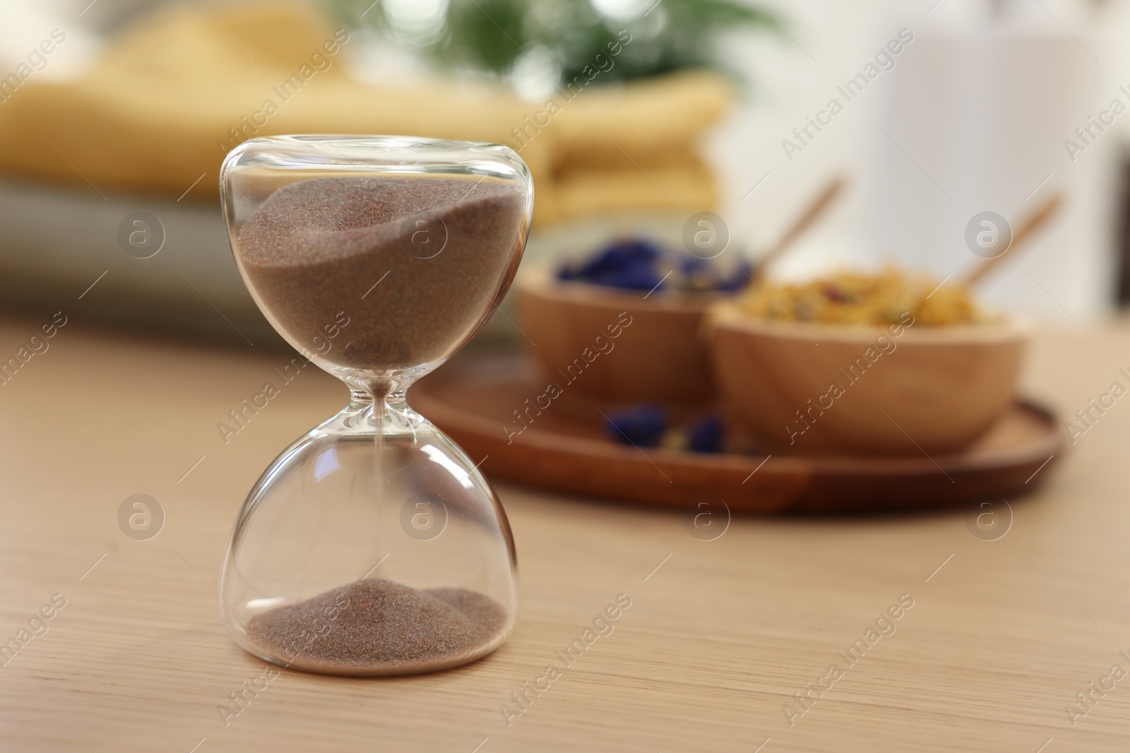 Photo of Sandglass on wooden table indoors, closeup. Spa time