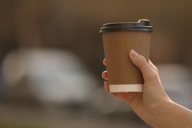 Woman with takeaway coffee cup outdoors, closeup. Space for text