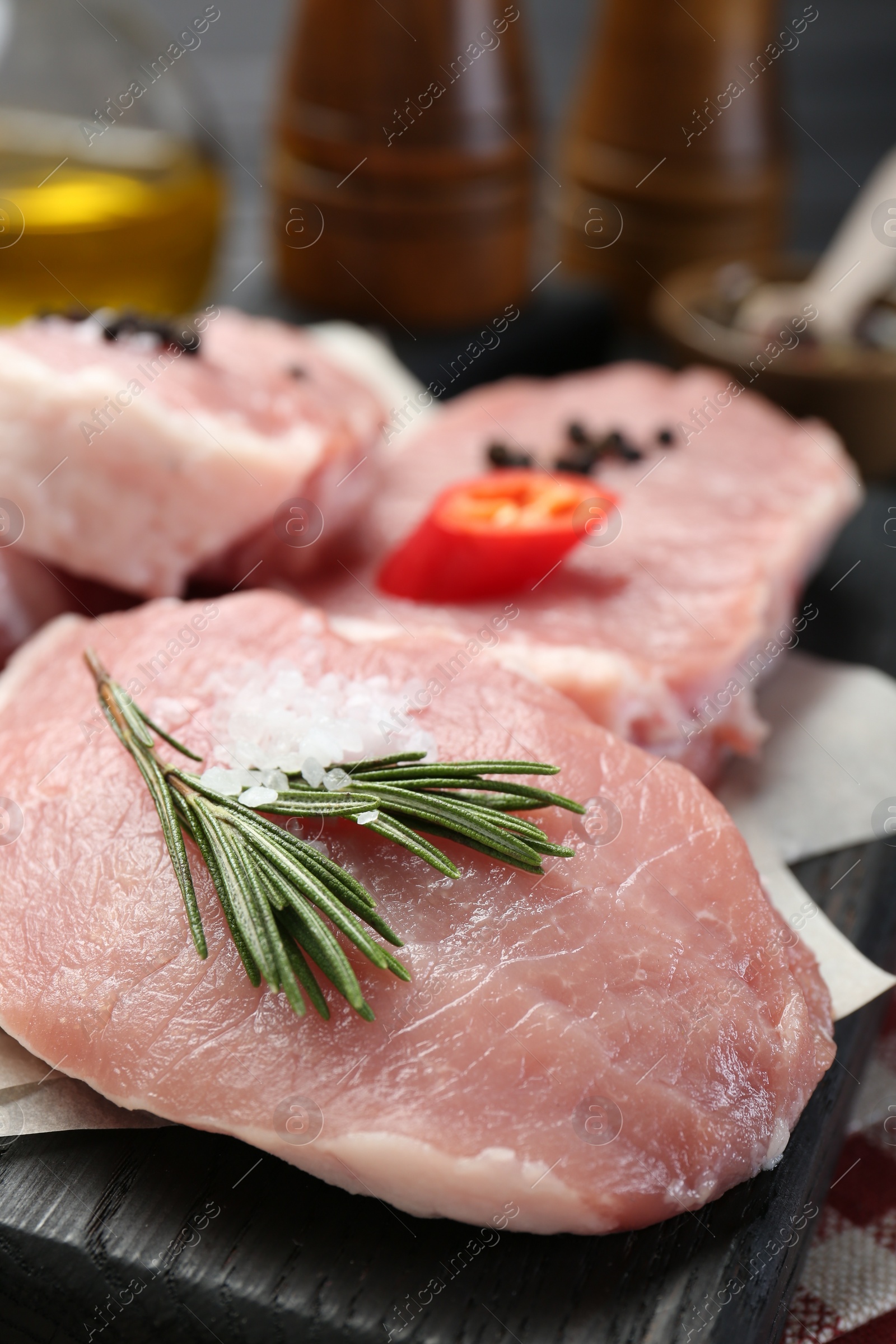 Photo of Pieces of raw pork meat with chili pepper and spices on board, closeup