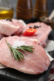 Photo of Pieces of raw pork meat with chili pepper and spices on board, closeup