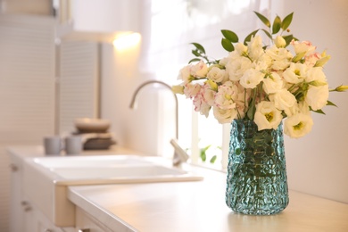 Bouquet of beautiful flowers on countertop in kitchen, space for text. Interior design
