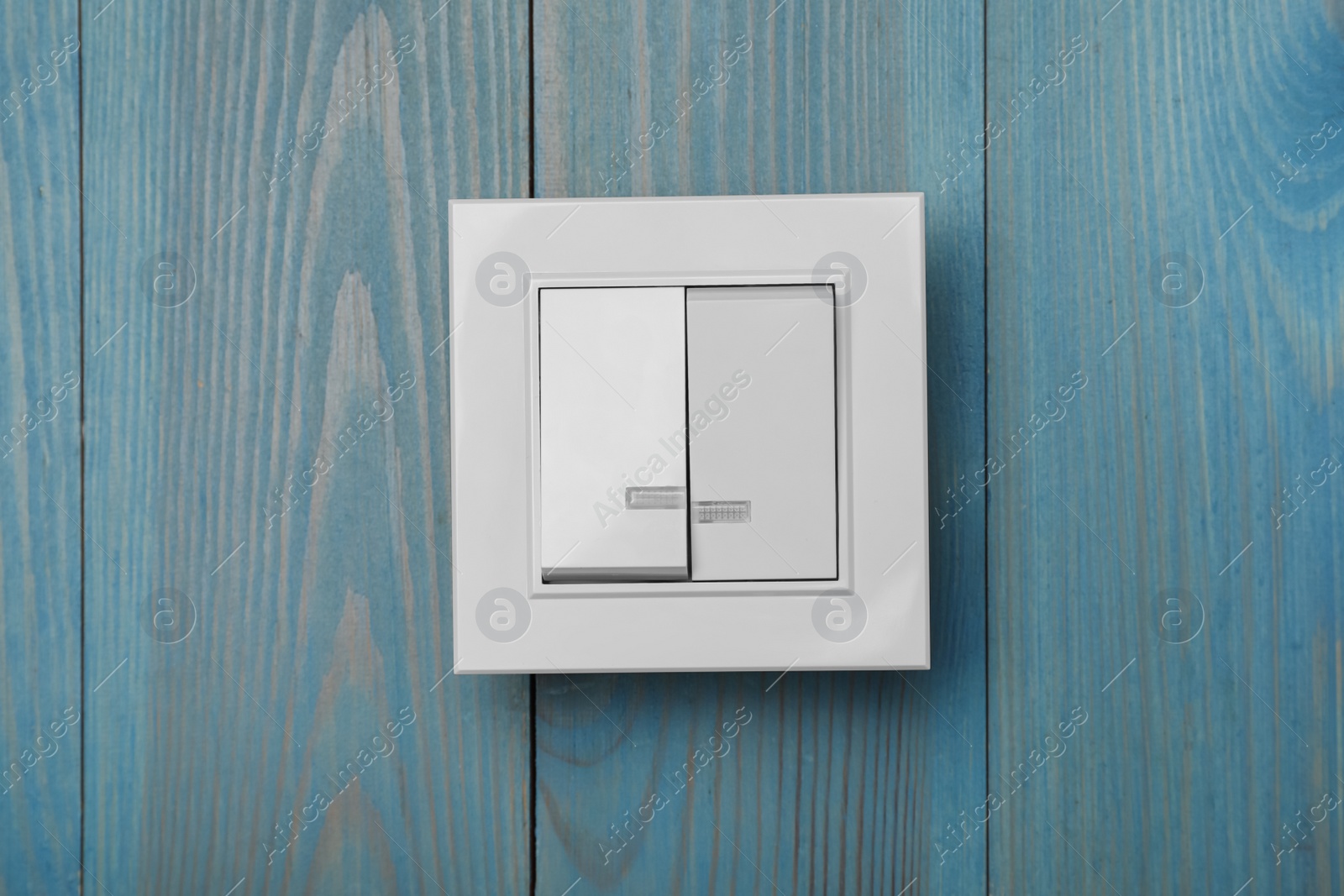 Photo of White light switch on turquoise wooden background