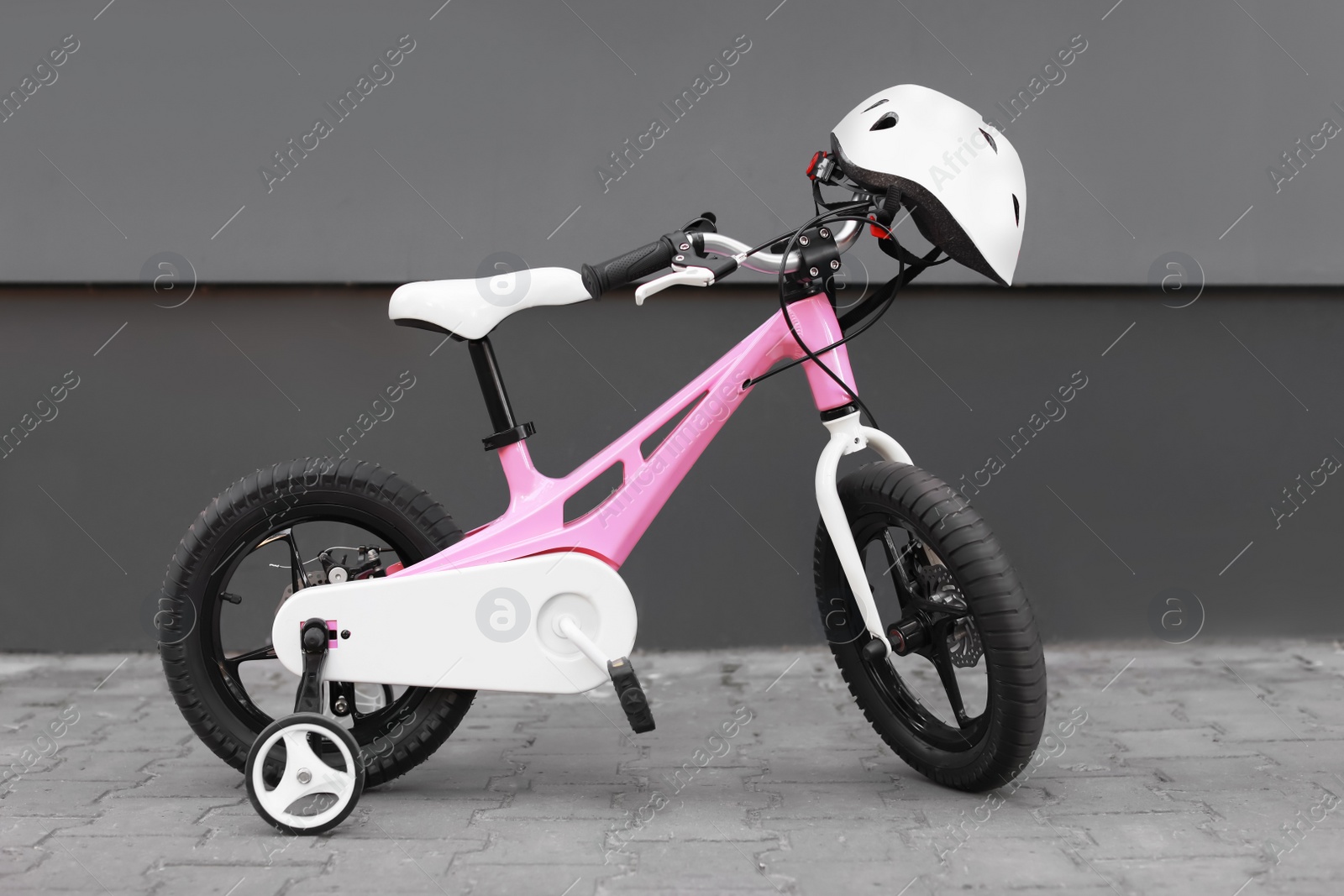 Photo of Pink bicycle for girl against gray wall on street