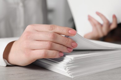 Woman stacking documents at table in office, closeup