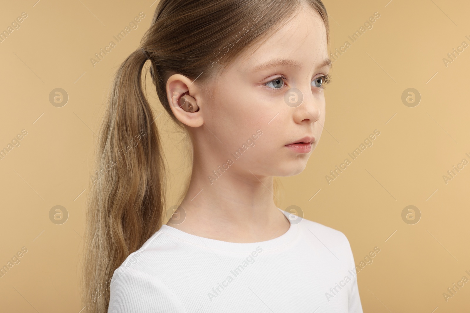 Photo of Little girl with hearing aid on pale brown background