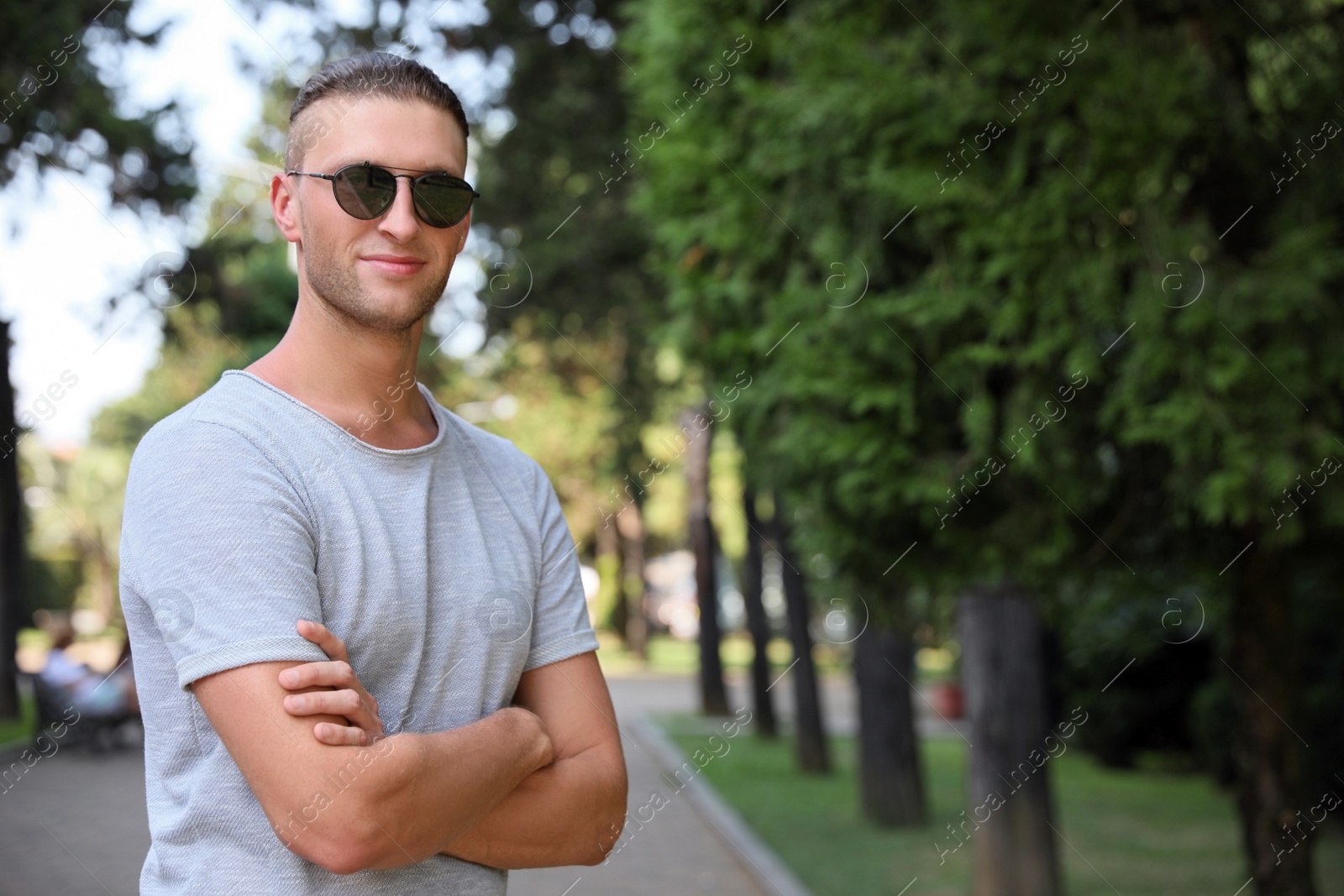 Photo of Handsome young man in stylish sunglasses at park, space for text