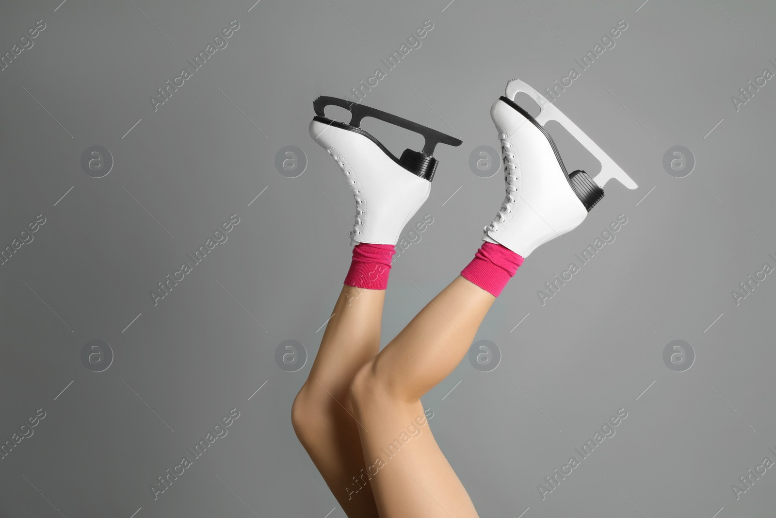 Photo of Woman in elegant white ice skates on grey background, closeup of legs. Space for text