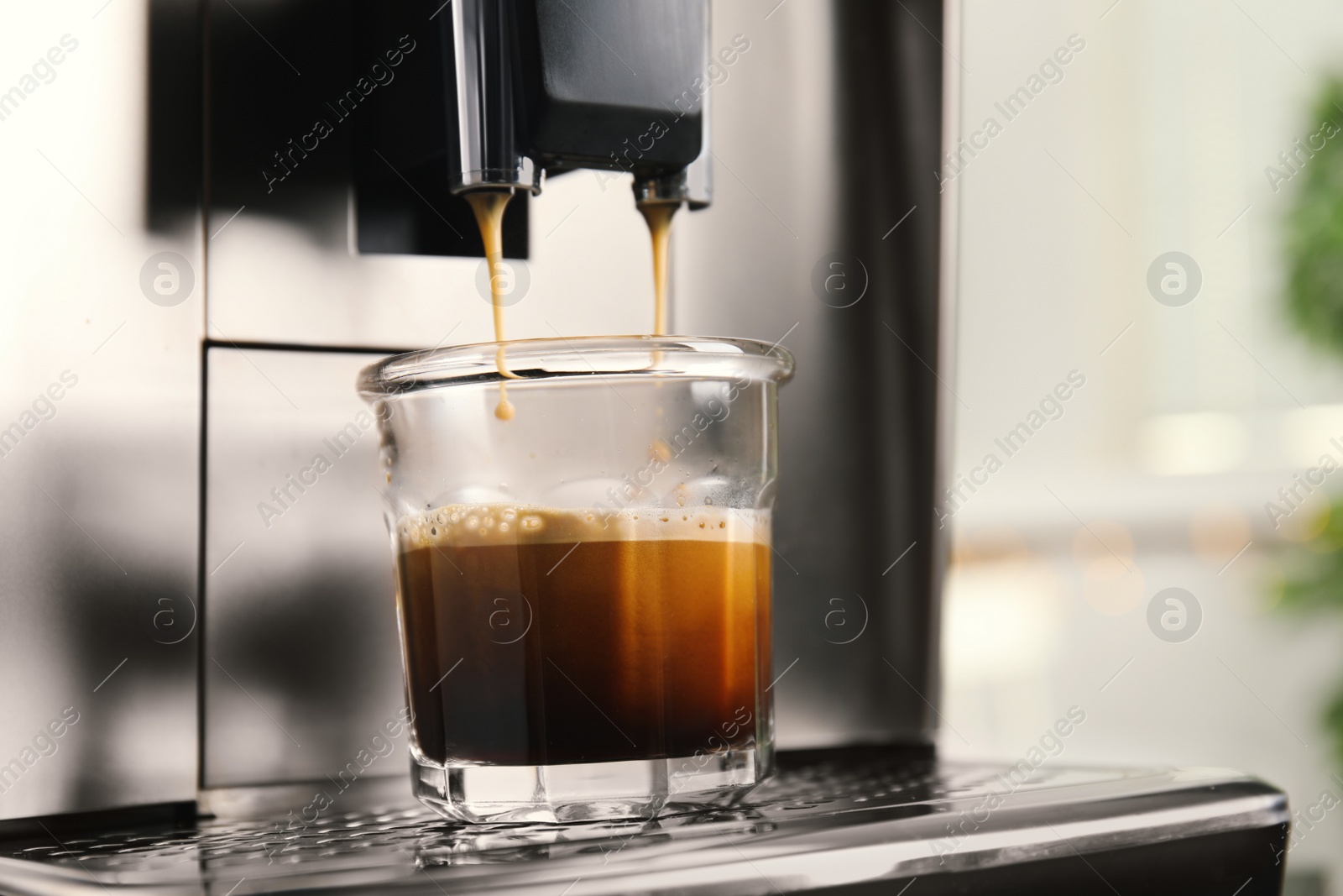 Photo of Espresso machine pouring coffee into glass against blurred background, closeup. Space for text