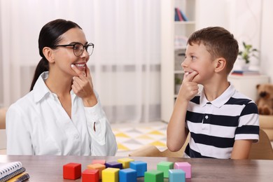 Photo of Dyslexia treatment. Speech therapist working with boy at table in room