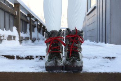Photo of Woman in comfortable boots on snowy day outdoors, closeup. Winter vacation