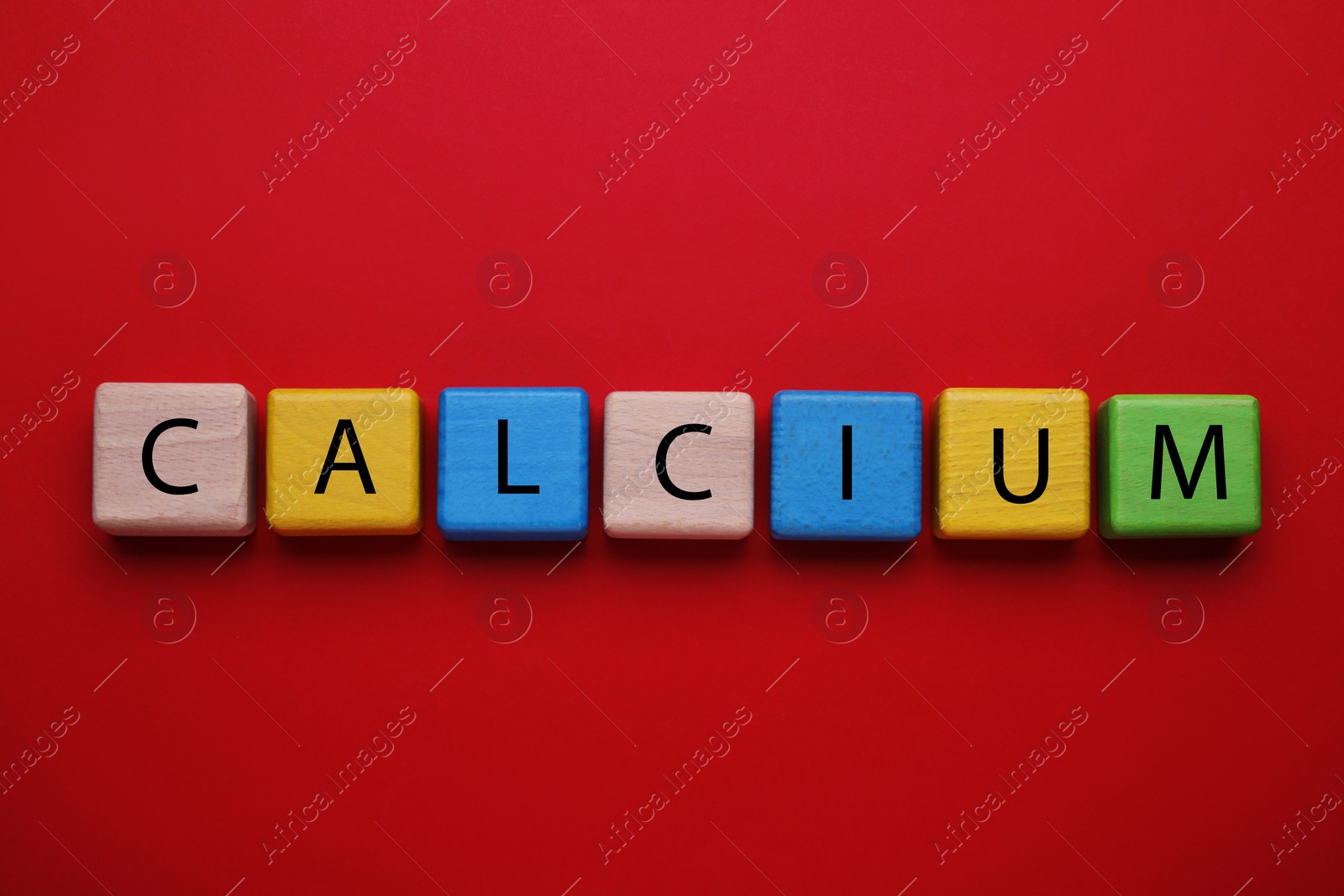 Photo of Word Calcium made of colorful wooden cubes with letters on red background, flat lay