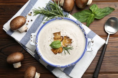 Photo of Delicious homemade mushroom soup served on wooden table, flat lay