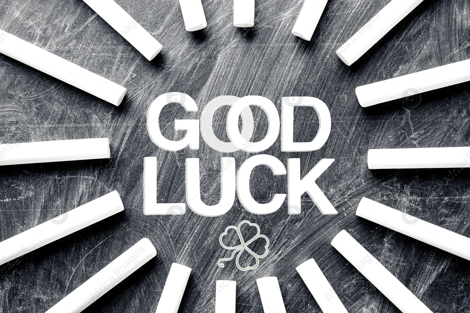 Image of Pieces of white chalk and phrase GOOD LUCK on blackboard, flat lay