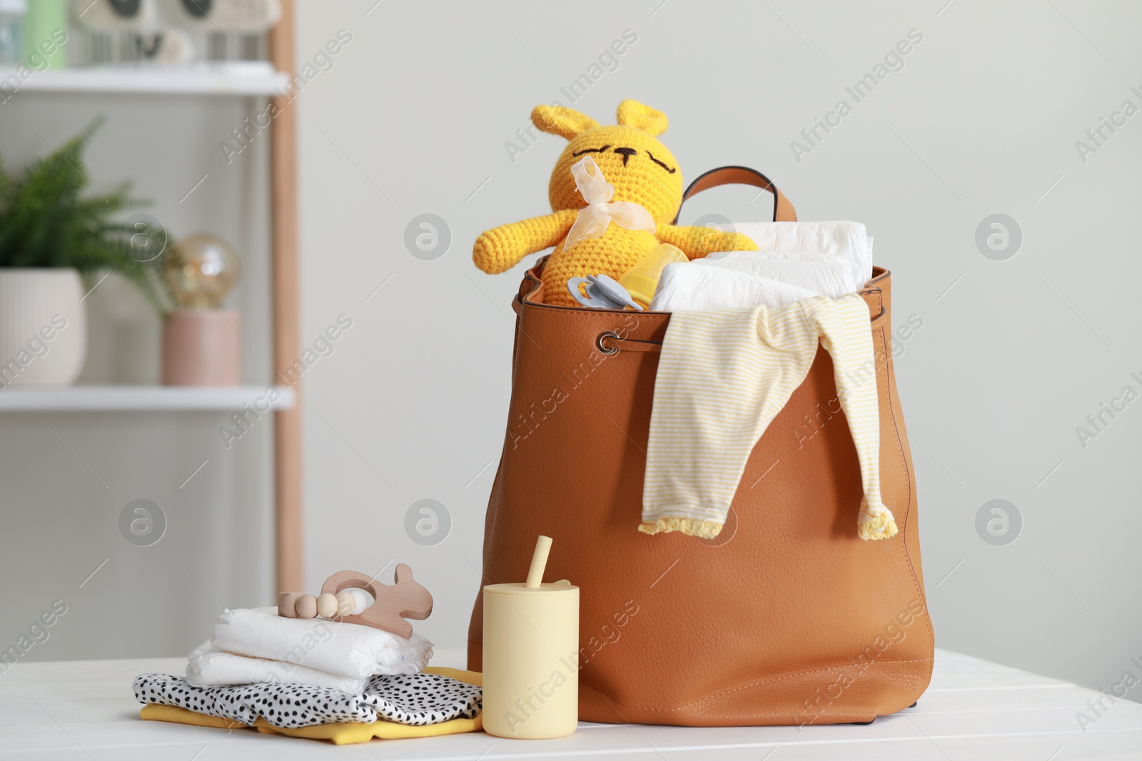 Photo of Mother's bag with baby's stuff on white wooden table indoors