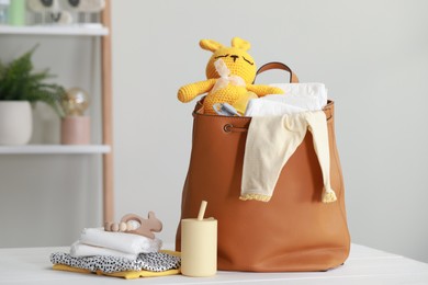 Photo of Mother's bag with baby's stuff on white wooden table indoors