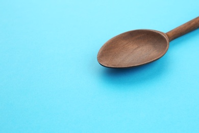 Clean empty wooden spoon on blue background, space for text