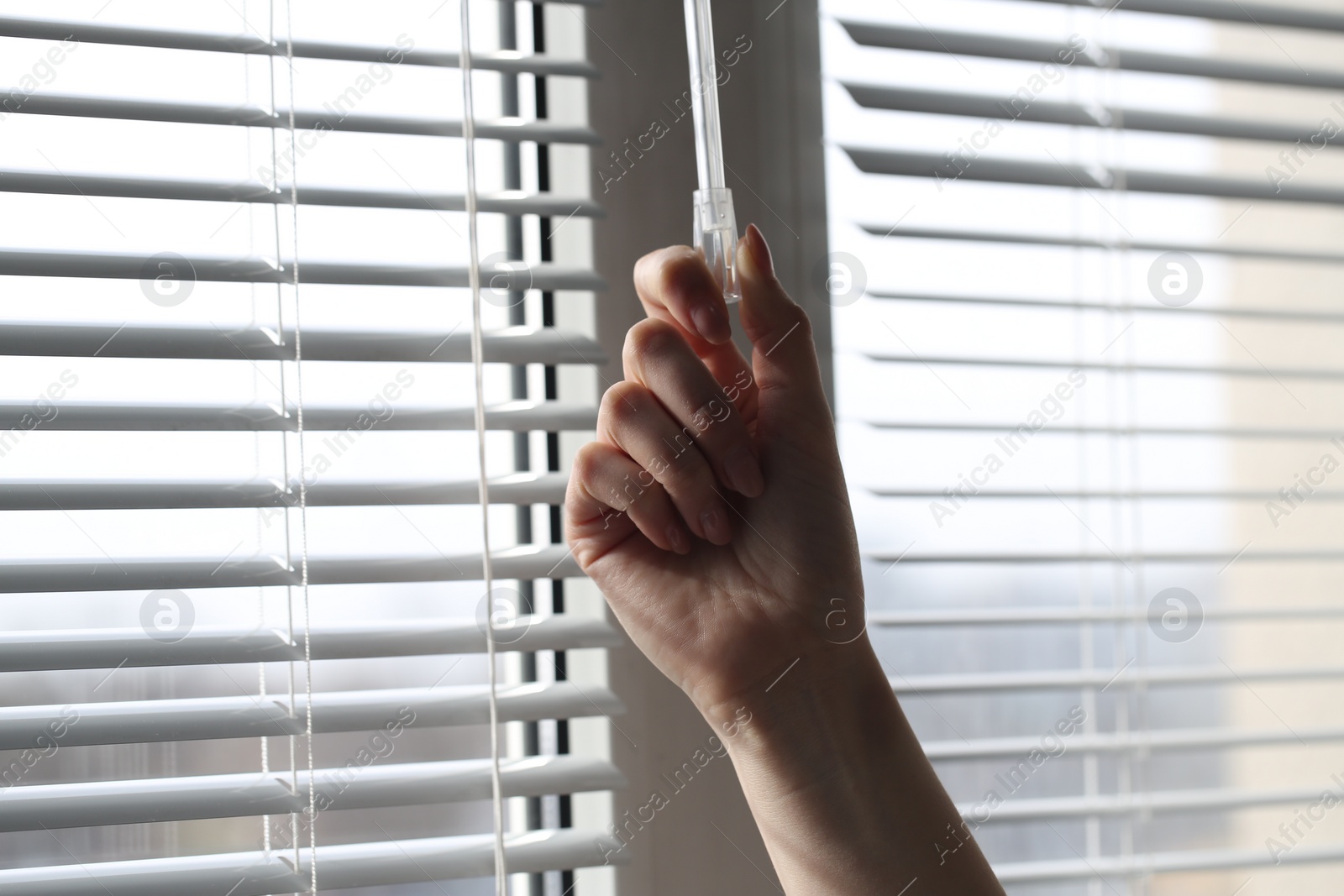 Photo of Woman opening white blinds at home, closeup