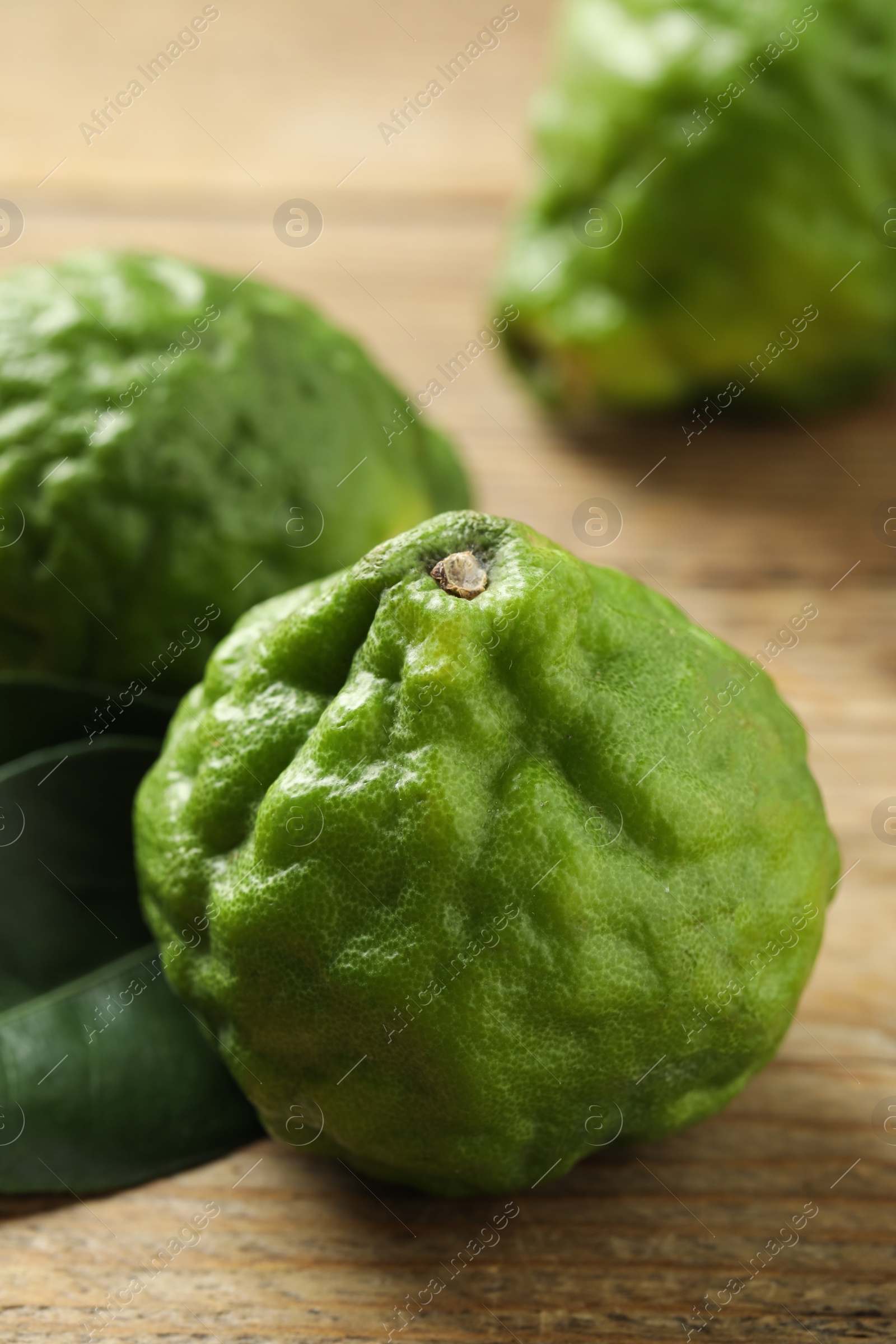 Photo of Fresh ripe bergamot fruits on wooden table, closeup