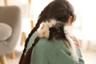Little girl with guinea pig at home, back view. Childhood pet