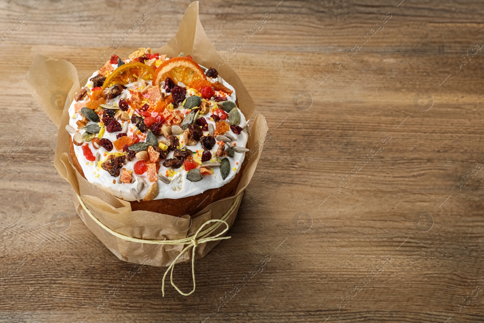 Photo of Traditional Easter cake with dried fruits on wooden table, space for text