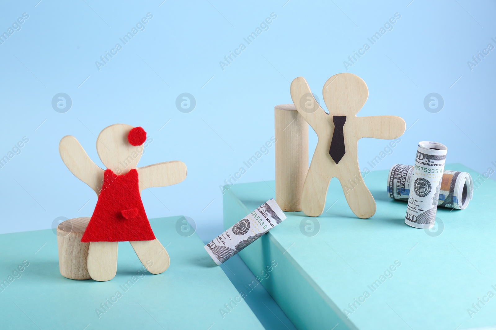 Photo of Gender pay gap. Wooden figures of man and woman with dollar banknotes on color background