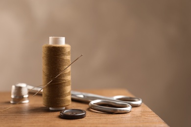 Photo of Scissors and other sewing accessories on wooden table, space for text