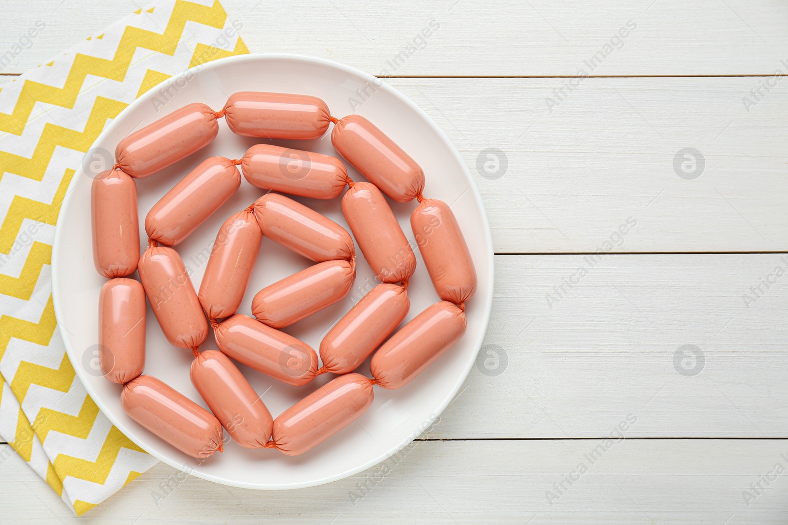 Photo of Delicious sausages on white wooden table, top view. Space for text