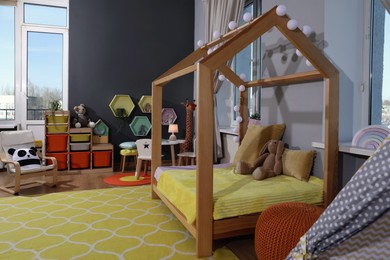 Photo of Stylish child room interior with comfortable house bed and toys