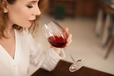 Photo of Woman with glass of wine at table in restaurant