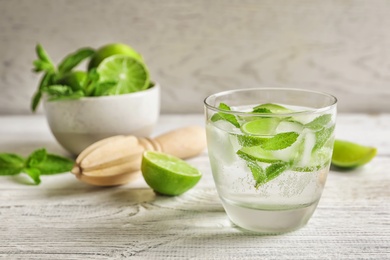 Refreshing beverage with mint and lime in glass on table